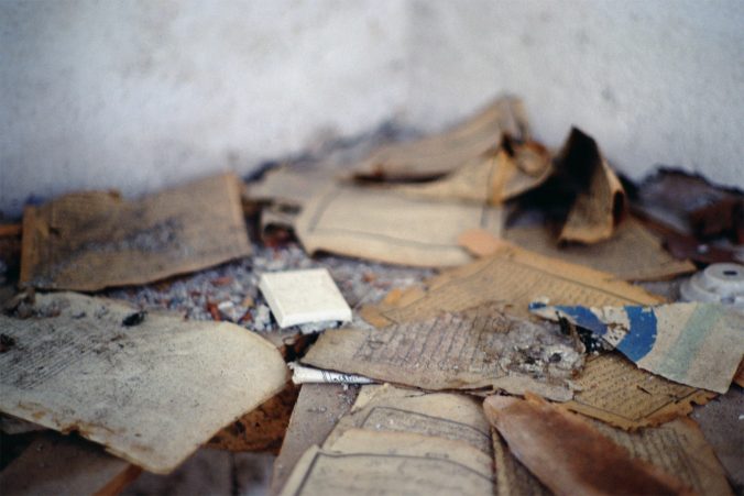 Close-up image of torn and desecrated pages from Qur'ans and religious books, inside the burned-out village mosque.